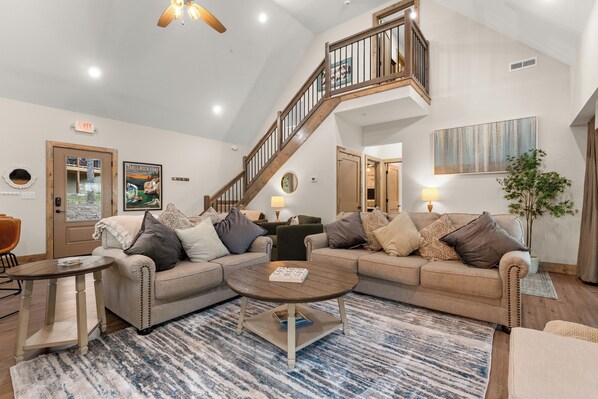 Ein geräumiges Wohnzimmer mit einer großen Eckcouch, einem Couchtisch und einer Treppe, die zu einer oberen Ebene führt.