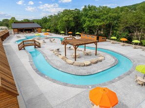 Ein Poolbereich mit Liegestühlen, Sonnenschirmen und einer Holz-Pergola.