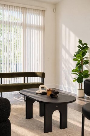 A modern living room with a dark round table, a bench, and a potted plant. - Spacious & Central 2BD in DT Dallas (Dallas)