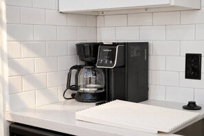 A black coffee maker with a digital display on a white countertop. - Spacious & Central 2BD in DT Dallas (Dallas)