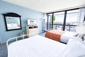 Een hotelkamer met een bed, een dressoir, een spiegel en een raam met uitzicht op de stad.