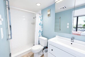 Een moderne badkamer met een douche, toilet en wastafel.