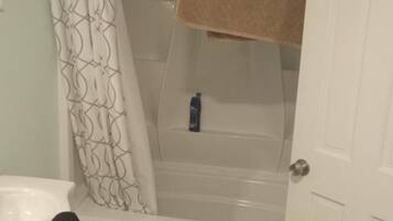 Ein Badezimmer mit einer Badewanne, einer Duschkabine, einem Handtuch und einer Tür.