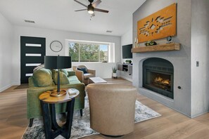 Un salon moderne avec une cheminée, un ensemble de canapés, une table basse et une table d’appoint.