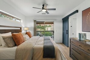 Una camera da letto con un letto, una ventola a soffitto, un comodino, una cassettiera e vista sull'esterno.