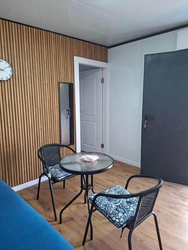 A room with a round table, two chairs, a clock on the wall, and a door.