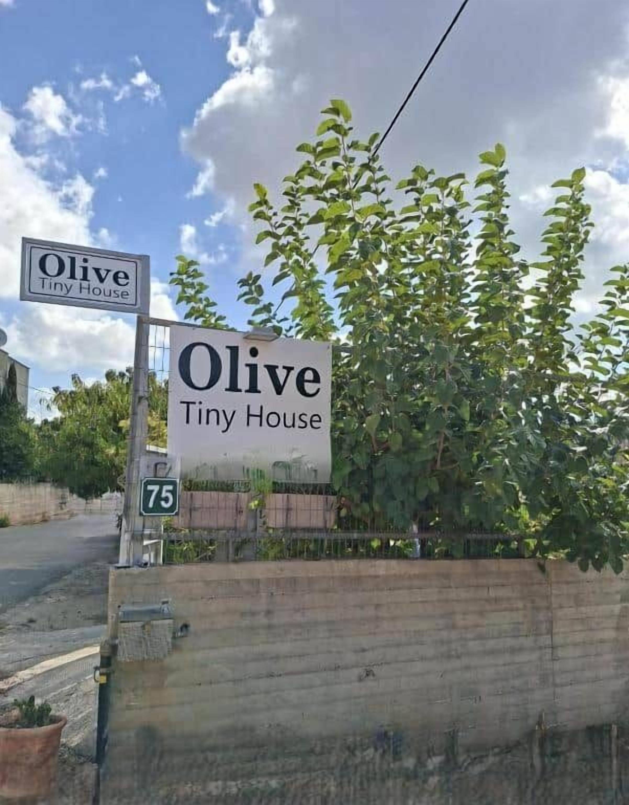 A sign for 'Olive Tiny House' with a road number 75.