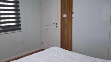 Un dormitorio con cama, puerta y ventana con persianas.