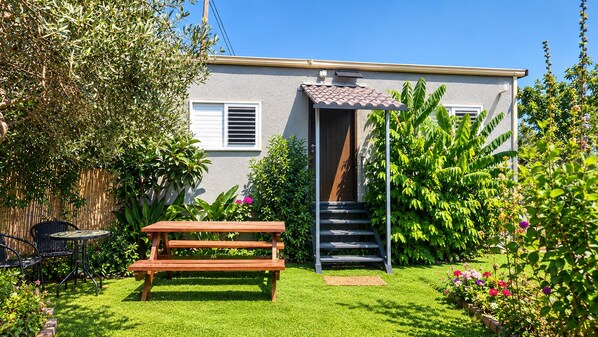 A residential property with a wooden bench, a staircase leading to a door, and a garden with various plants.