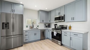 Een moderne keuken met grijze kastjes, roestvrijstalen apparatuur en een houten vloer.