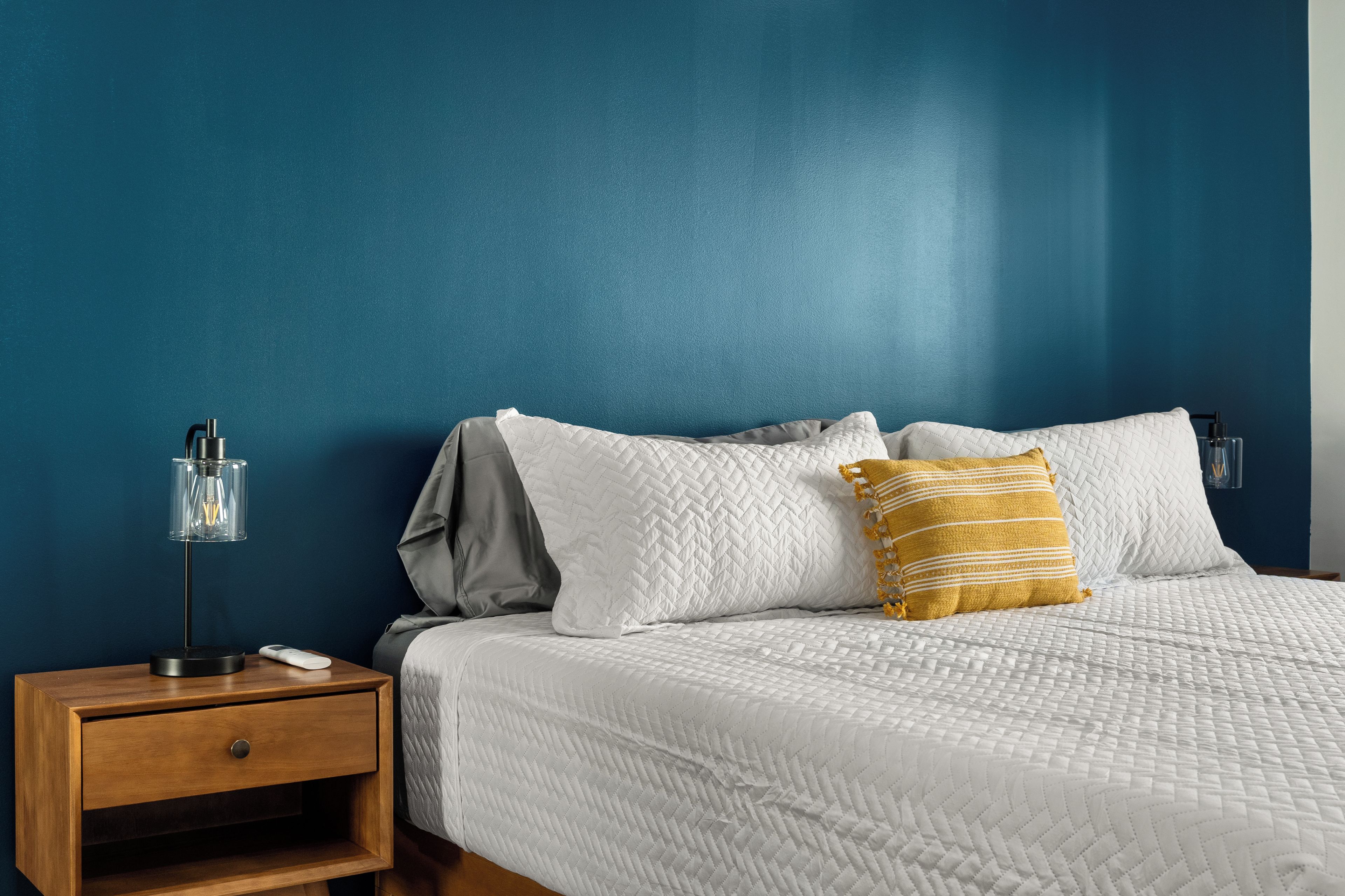 Une chambre à coucher comprenant un lit, une table de chevet, une lampe et un meuble mural.