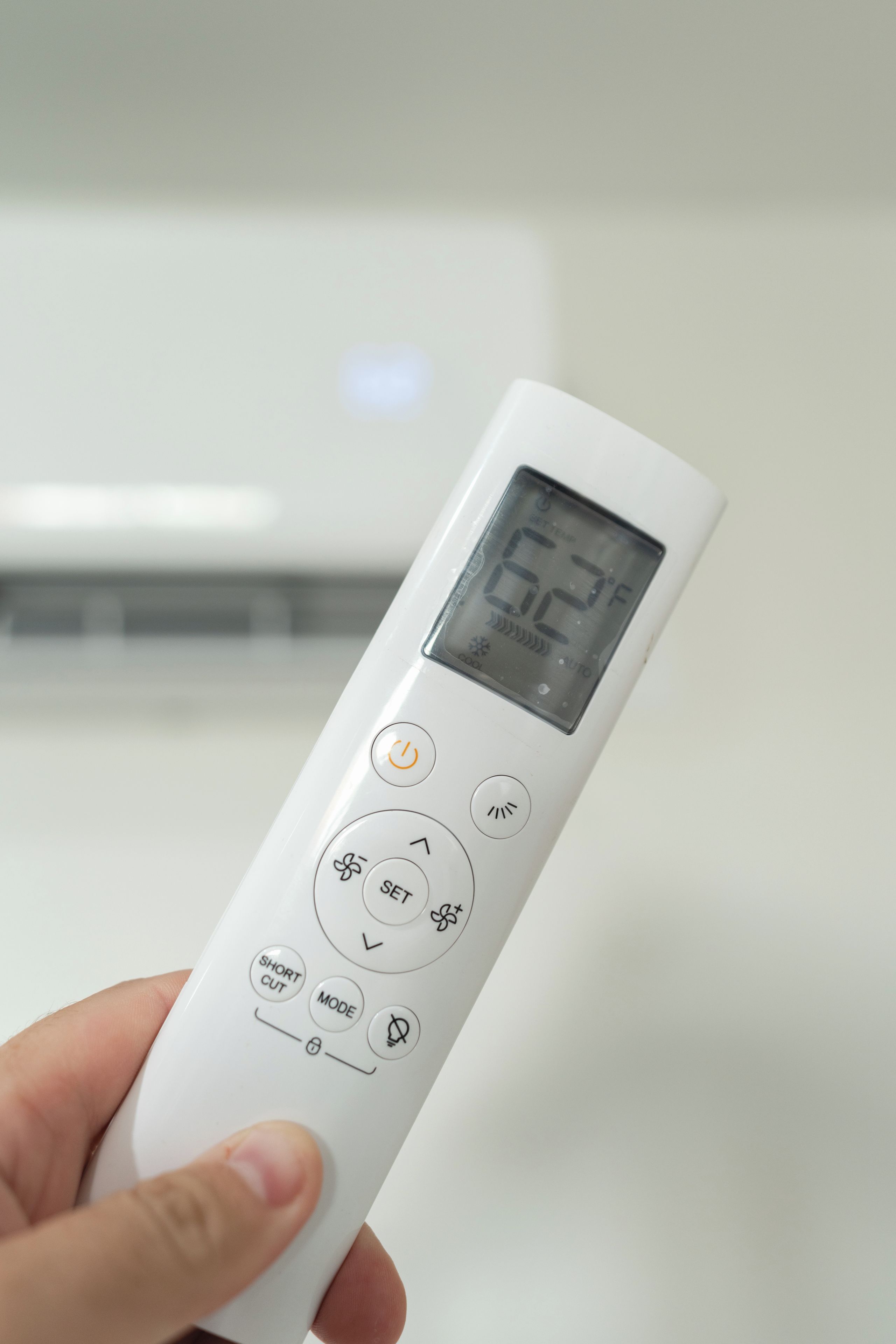 A white remote control with a digital display, buttons for settings, and a power symbol.