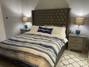 A bedroom with a tufted headboard, a striped bedspread, bedside lamps, and a bedside table with a tissue box. - Celebrity Lifestyle / Dream36 Montego bay Jamaica (Montego Bay)