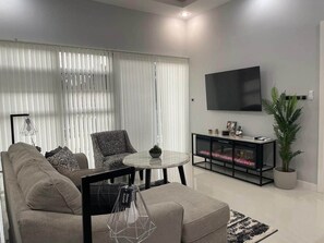 A modern living room with a sofa, a round coffee table, a TV, and a plant. - Celebrity Lifestyle / Dream36 Montego bay Jamaica (Montego Bay)