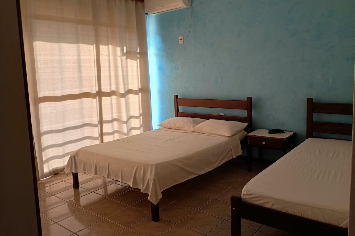 Een kamer met twee bedden, een nachtkastje en een raam met gordijnen.