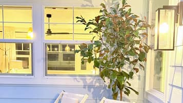 Two white lounge chairs positioned on a patio with a potted plant nearby.