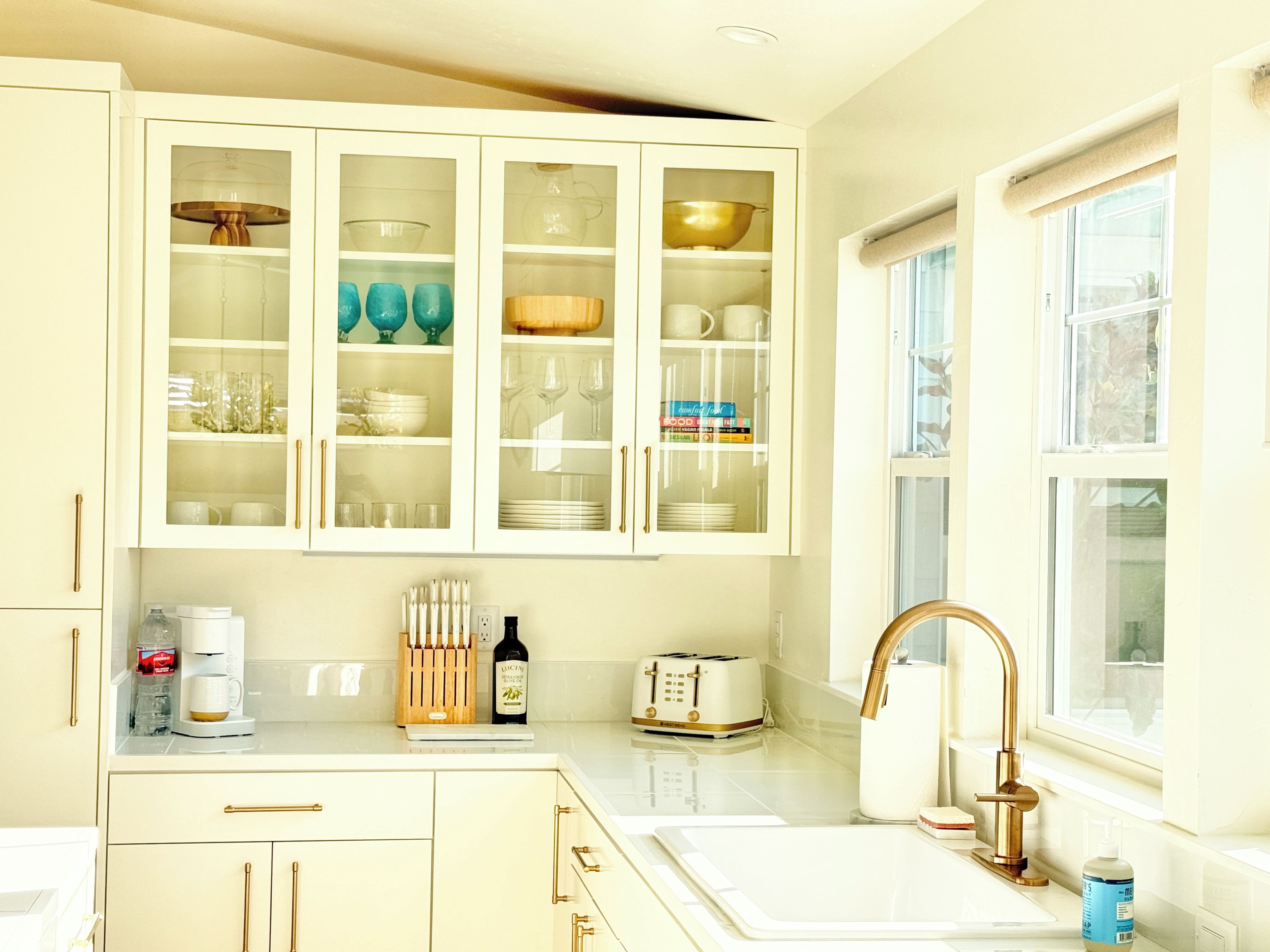 A kitchen with white cabinets, a sink, a window, and a toaster.