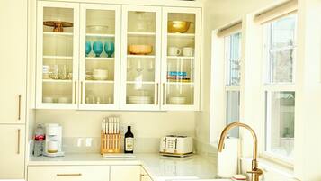 A kitchen with white cabinets, a sink, a window, and a toaster.