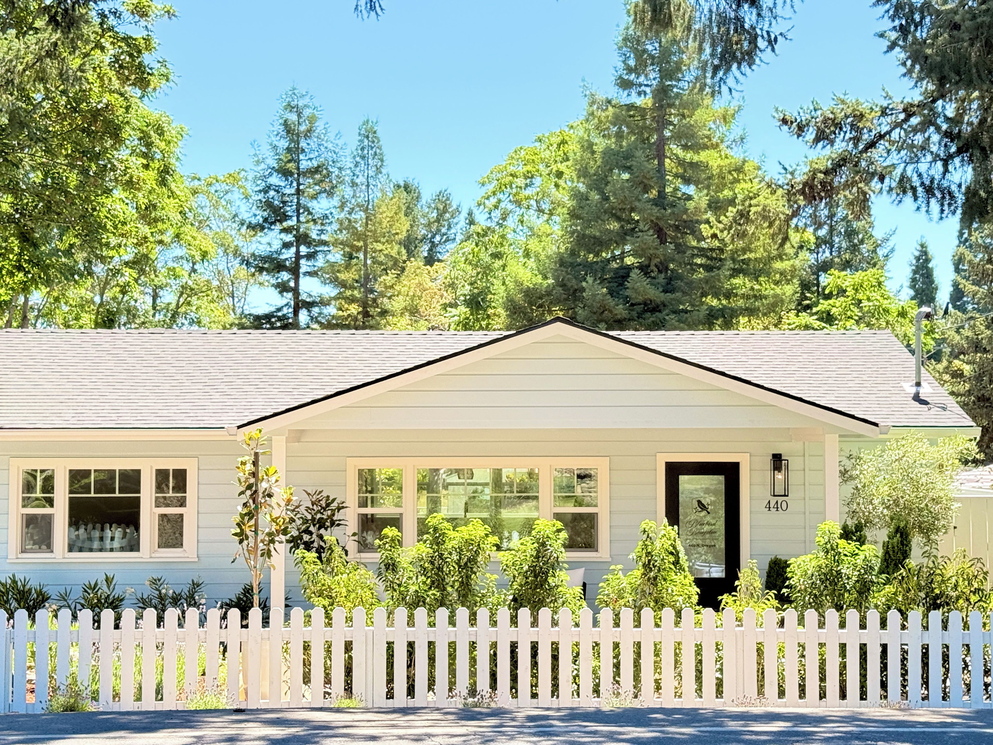 A single-story house with a white picket fence, a front porch, and a mailbox.