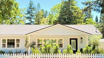 A single-story house with a white picket fence, a front porch, and a mailbox.
