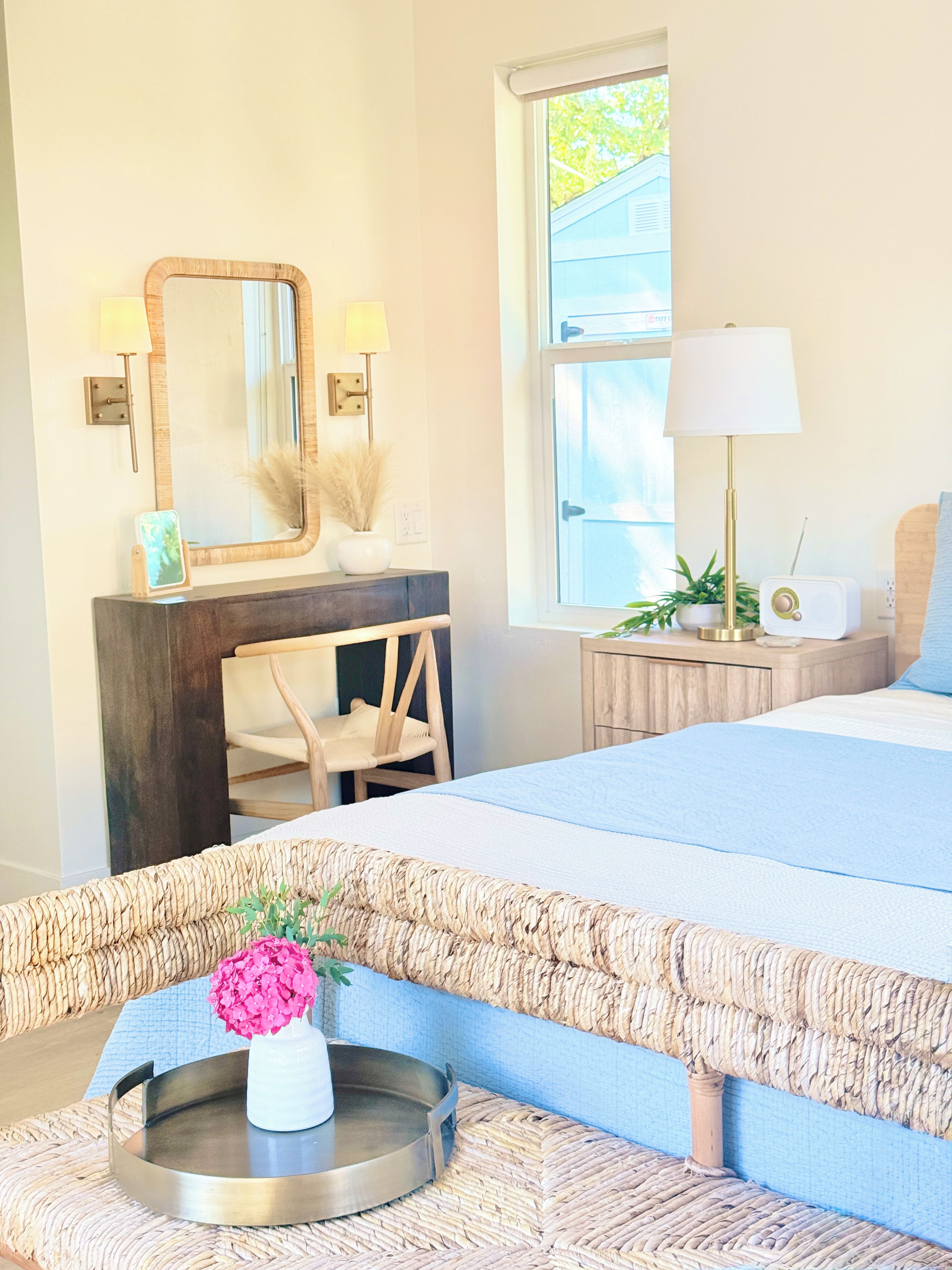 A bedroom with a bed, a dresser, a mirror, a lamp, and a window.