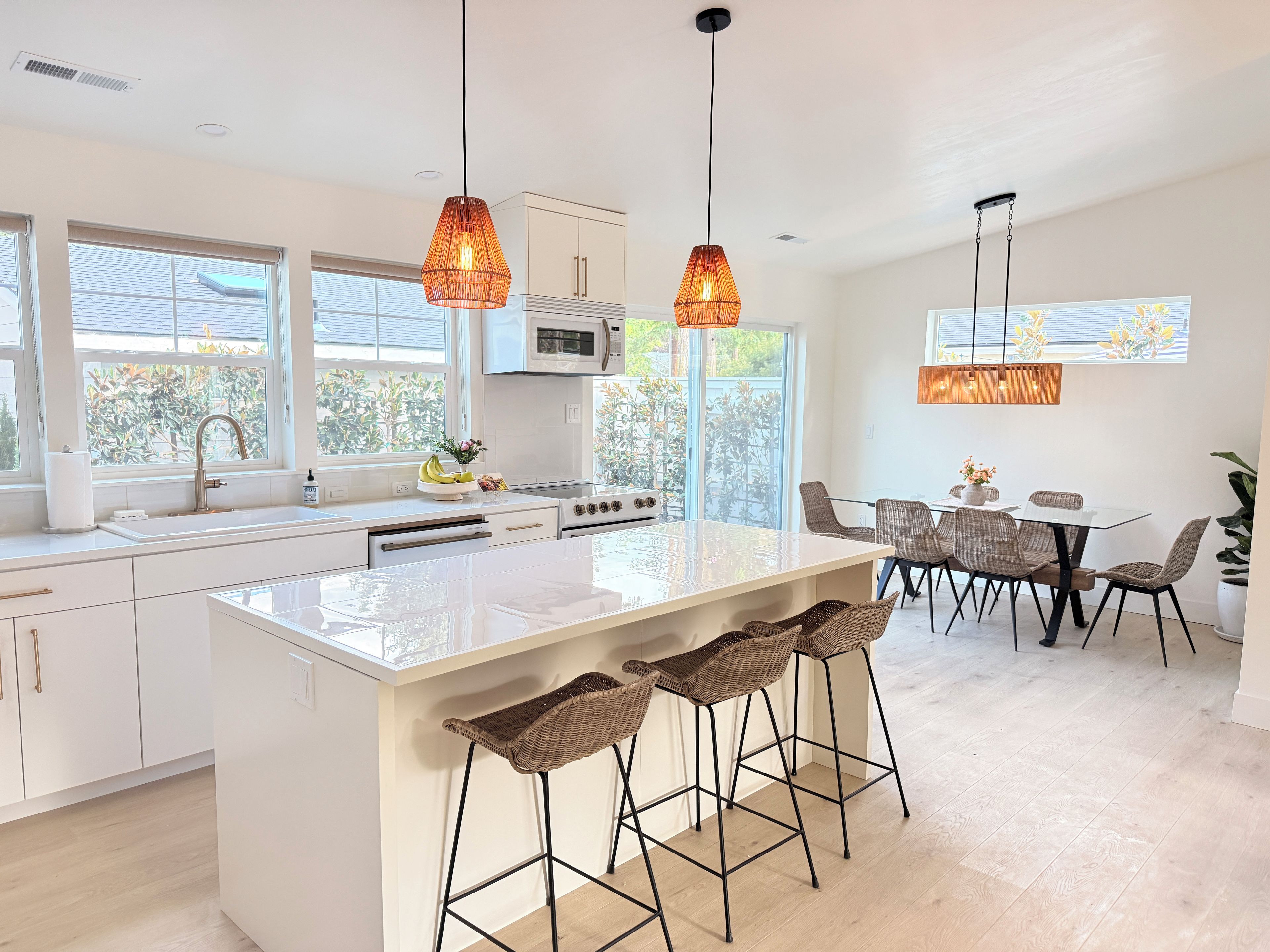 A modern kitchen with a central island, bar stools, and pendant lighting.