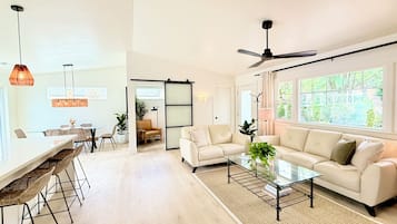 A spacious living area with a sofa, coffee table, and dining area with chairs.