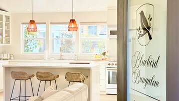 A modern kitchen with pendant lights, a central island, and a view of greenery outside.