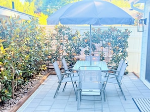 An outdoor patio with a table and chairs, surrounded by plants and a fence. - Bluebird Bungalow- Renovated Mid-Century Dream in the Historic Core of J-Ville! (Jacksonville)