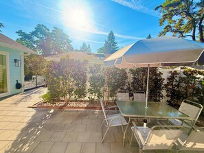 An outdoor patio with a table and chairs, surrounded by plants and trees. - Bluebird Bungalow- Renovated Mid-Century Dream in the Historic Core of J-Ville! (Jacksonville)