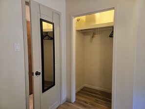 A hallway with a white door, a mirror, and a closet with hanging clothes. - Quiet oak-lined retreat in Garden Ridge - 4BR home (Garden Ridge)