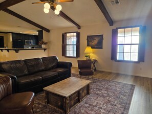 A living room with a leather sofa, a wooden coffee table, a patterned rug, a lamp, and a painting on the wall. - Quiet oak-lined retreat in Garden Ridge - 4BR home (Garden Ridge)
