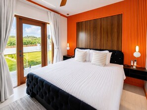 A bedroom with a large bed, a view of the outdoors, and a wooden headboard. - Villa Camila Unit 1: Modern, Central Villa with Tranquil Charm (Cooper Jack Bay Settlement)