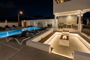 A modern outdoor pool area with lounge chairs and a fire pit. - Villa Camila Unit 1: Modern, Central Villa with Tranquil Charm (Cooper Jack Bay Settlement)