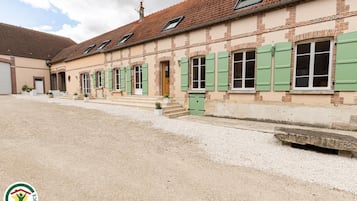 A building with multiple windows, a gravel driveway, and a small garden area.