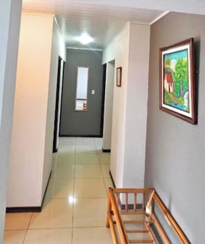 A hallway with a wooden bench, a framed picture on the wall, and a door at the end. - Costa Rica explorer  (Grecia)