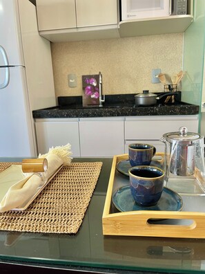 Una cucina con forno a microonde, fornelli e un vassoio con tazze e teiera.