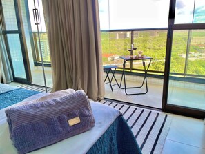 Una camera d'albergo con un letto, una finestra con tende, un tavolino con una sedia e vista sulla città.