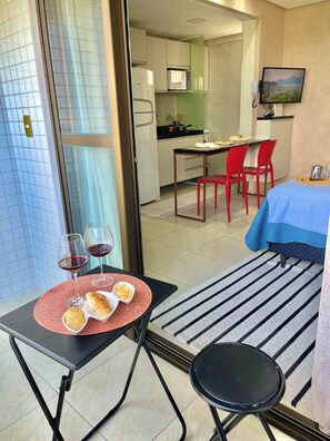 Camera d'albergo con zona pranzo, angolo cottura e un letto con copriletto blu.