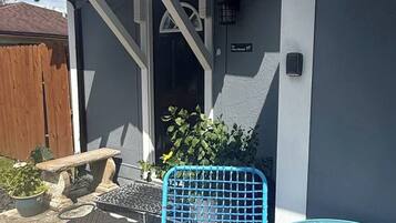 A patio area with a blue chair, a small table, and a wooden bench.