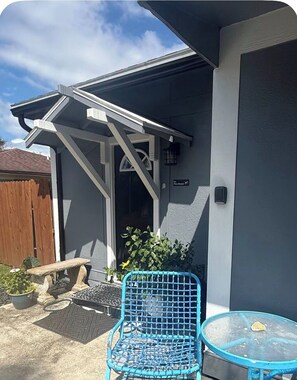 A patio area with a blue chair, a small table, and a wooden bench. - Surf Escape: Cozy 1-bedroom studio in tranquil Ponte Vedra Beach FL with AC (Palm Valley)