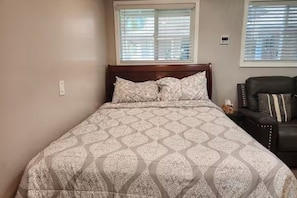 A bedroom with a bed, a window, and a chair. - Cozy Private Casita Near RUHS with Full Kitchen, Laundry and Parking (Moreno Valley)