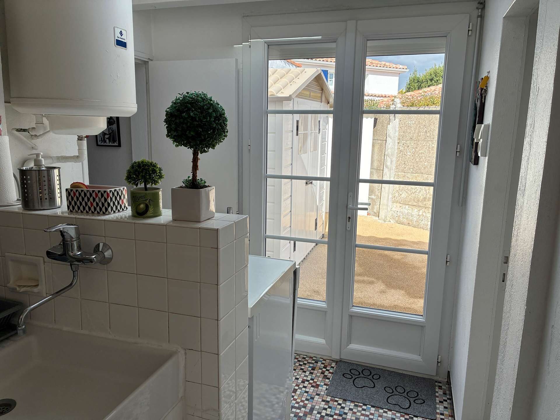 Een schone, moderne badkamer met douche, wastafel en toilet. Op het aanrecht staat een kleine potplant en er is een raam met uitzicht op een achtertuin.