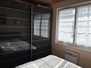 Ein Schlafzimmer mit einem Bett, einem Kleiderschrank und einem fenster mit Vorhängen.