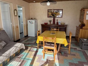 Un salon confortable avec un canapé, une table à manger avec des chaises, un coin cuisine avec un réfrigérateur et un sol à motifs.