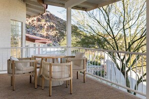Un espace extérieur aménagé, abrité et doté de mobilier en osier, offrant une vue sur un paysage montagneux.