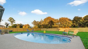 Ein Garten mit einem runden Pool, einem Holzzaun und Gartenmöbeln.