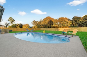 A backyard with a circular swimming pool, a wooden fence, and outdoor furniture.