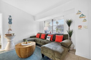 A living room with a sectional sofa, a wooden coffee table, and a decorative wall piece.