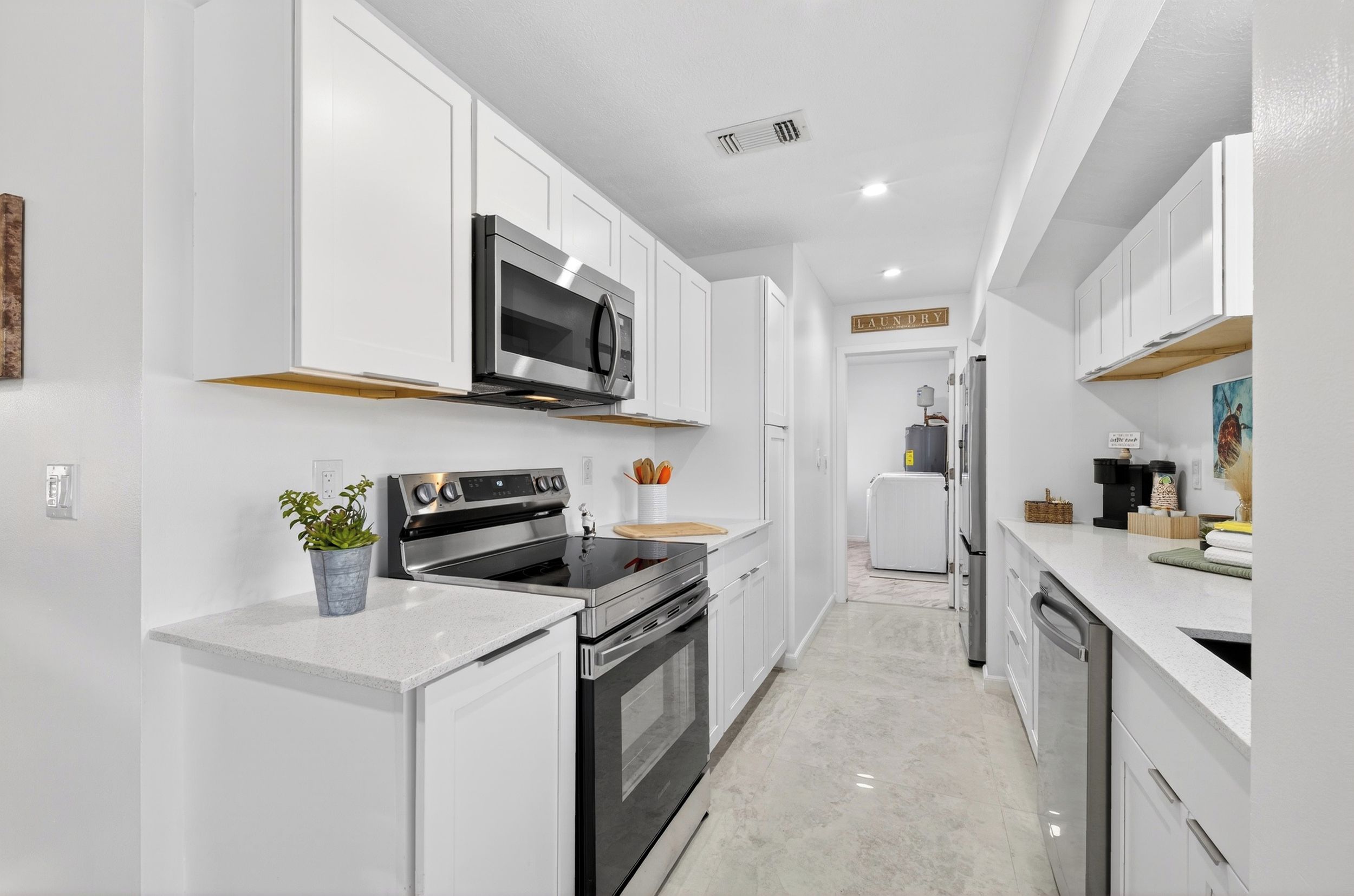 Una cocina moderna con armarios blancos, electrodomésticos de acero inoxidable y una isla central.